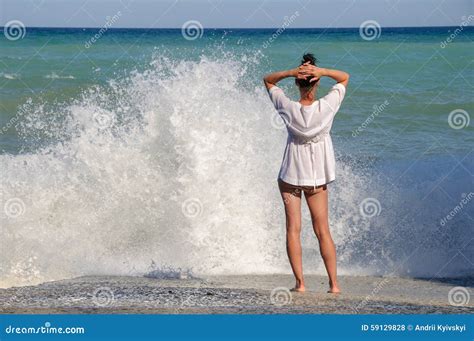 Young Woman Stands On The Sea Beach And Looks At Stock Photo Image Of