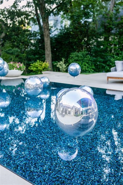 An Inflatable Ball Floating On Top Of A Swimming Pool Next To Lounge Chairs