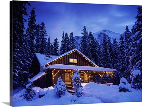 Snow Covered Cabin With Christmas Lights In The Mountains