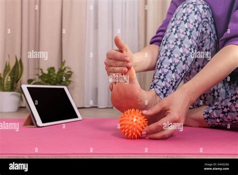 Girl Sits And Massages Her Foot With A Prickly Ball To Relax Looks At