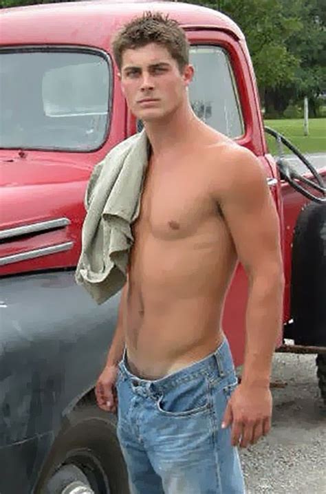 A Shirtless Man Standing Next To An Old Truck