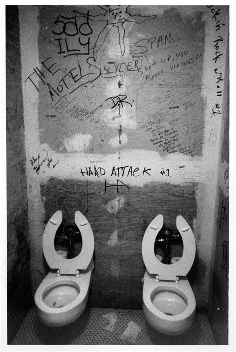 Two Toilets With Their Lids Open In A Bathroom Stall One Has Graffiti On The Wall
