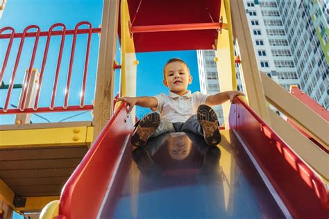 Little Boy Slides Down The Slide At Playground Stock Photo Image Of