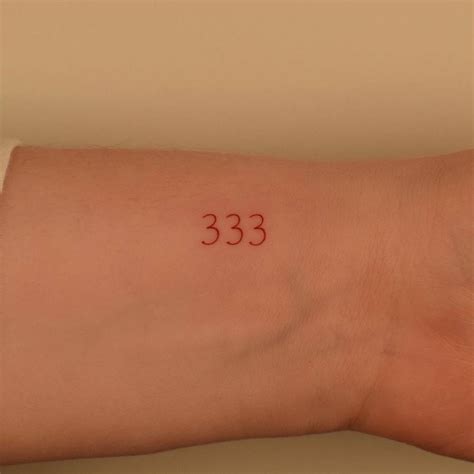 Number 333 Tattoo Located On The Wrist Done In Red