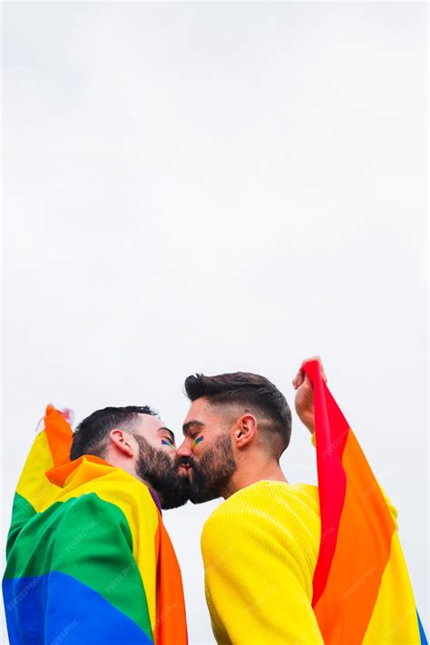 Casal Homossexual Beijando Coberto Com Bandeiras Lgbt Foto Grátis