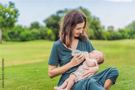 Mother Holding And Feeding Baby From Milk Bottle In The Park Portrait