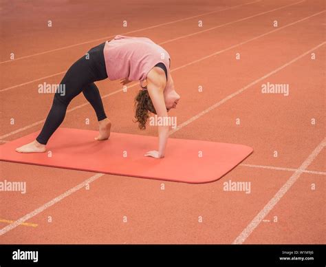 Woman Bending Over Backwards In Yoga Position At Athletics Hall On
