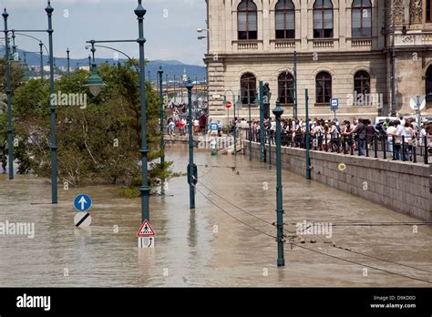 Spectators And Tourists Looking Over At The Flooded Street And Tram On The Burst Banks Of The