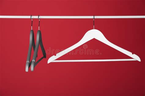 Empty Clothes Hangers On Metal Rail Against Color Background Stock