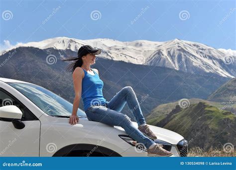 Young Woman Sitting On The Hood Of The Car And Enjoying The Surrounding