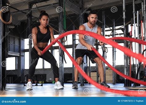 Athletic Young Couple With Battle Rope Doing Exercise In Functional