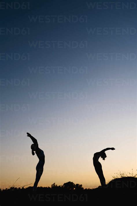 Women Bending Over Backwards While Practicing Yoga Outdoors Stock Photo