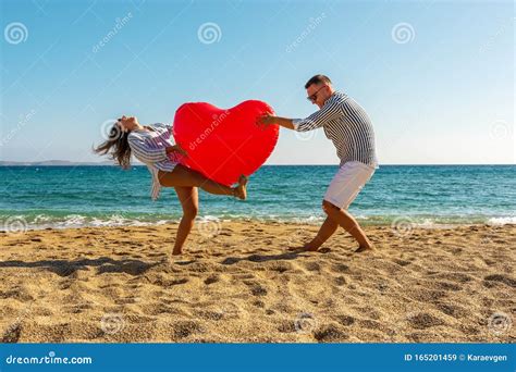 Young Couple Having Fun On The Beach With A Big Heart Balloon Summer