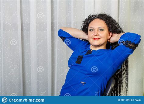 curly brunette woman in blue sits on a chair stock image image of resource happy 217118919