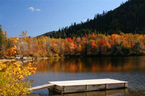 Colorful Autumn Trees Reflected In Mountain Lake With Boat Dock