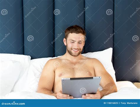 shirtless hunky man with beard lies naked in bed stock image 118016929