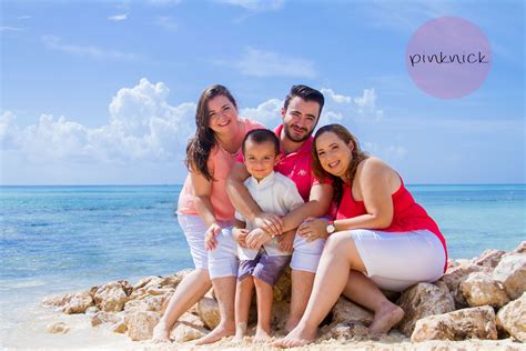 A Family Sitting On The Rocks At The Beach Posing For A Photo In Front Of The Ocean