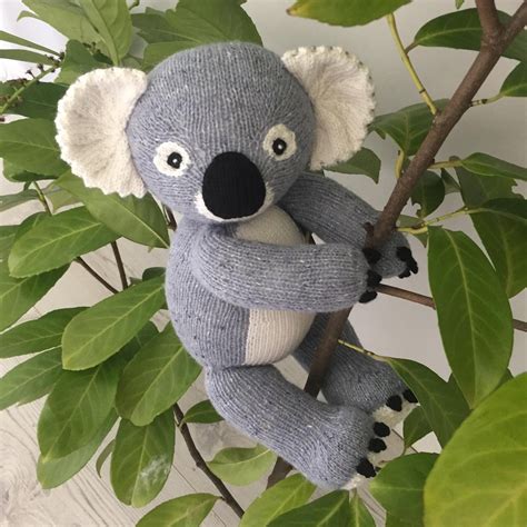 A Stuffed Koala Bear Sitting On Top Of A Tree Next To A Green Plant