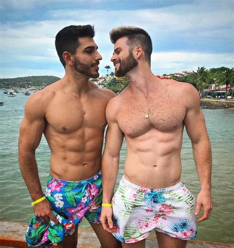 Two Men Standing Next To Each Other In Swim Trunks Near The Water With