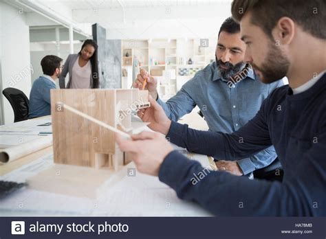 Male Architects Assembling Architectural Model In Office Stock Photo