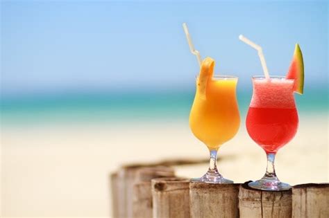Red And Orange Caribbean Cocktails On A Wooden Fence At The Beach