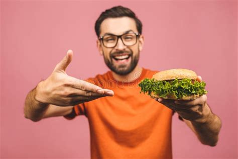 Young Man Holding A Piece Of Hamburger Student Eats Fast Food Burger