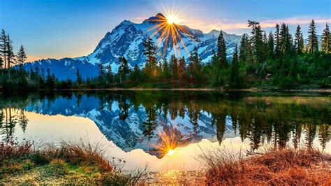 Landscape View Of White Covered Mountains Green Trees In Sunrise