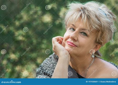 beautiful active caucasian mature woman about 62 years old is sitting on the bench marked for
