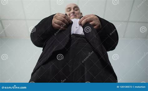 Overweight Male Trying To Fasten A Button On His Jacket Bottom View Of