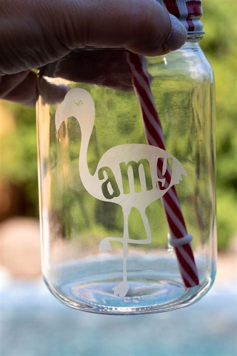 A Hand Holding A Straw In A Jar With A Flamingo On It And The Word Am