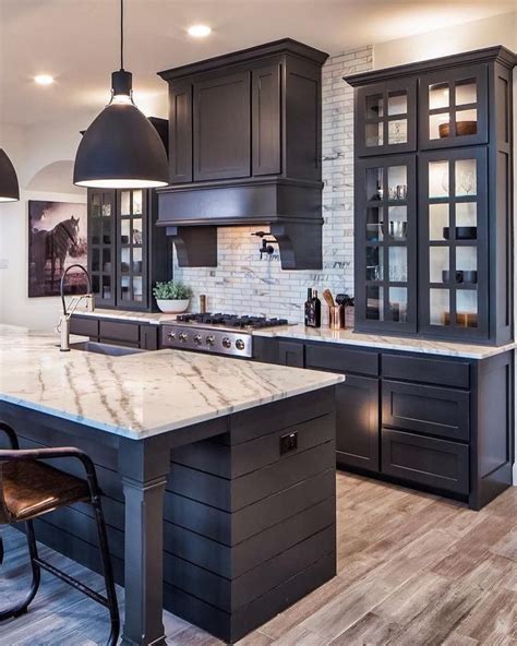 A Large Kitchen With Black Cabinets And Marble Counter Tops Along With