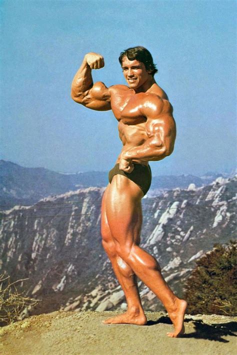 A Man Posing On Top Of A Mountain Flexing His Muscles