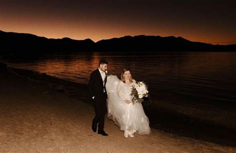 Groom Holding Brides Dress As They Walk Down Tahoe Lake Shore In 2023