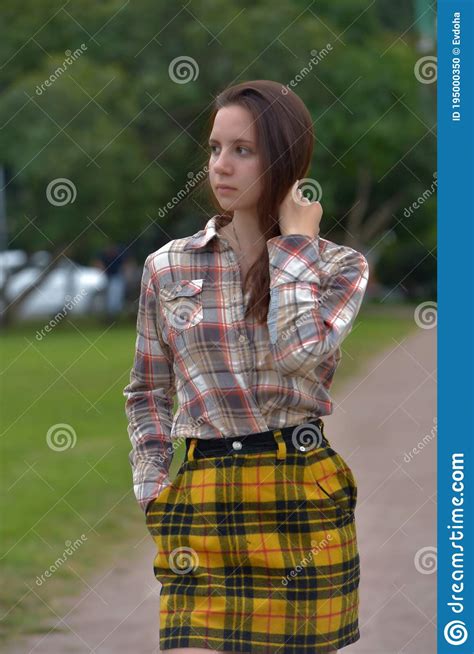 Slender Brunette Girl In A Plaid Skirt In The Summer In The Park Stock