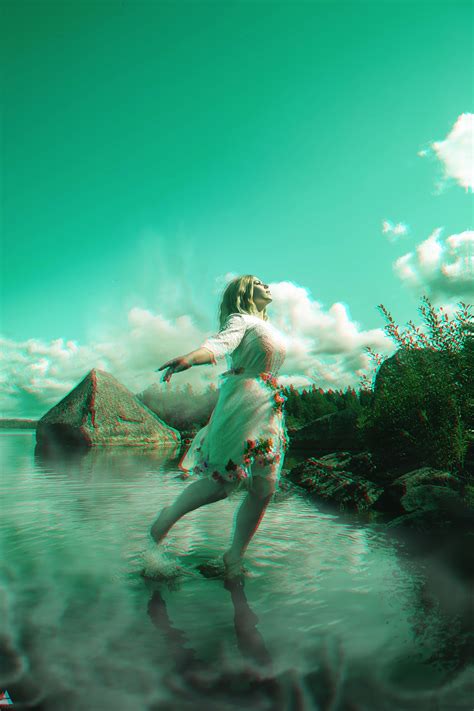 A Woman Is Walking In The Water Near Some Rocks And Grass While