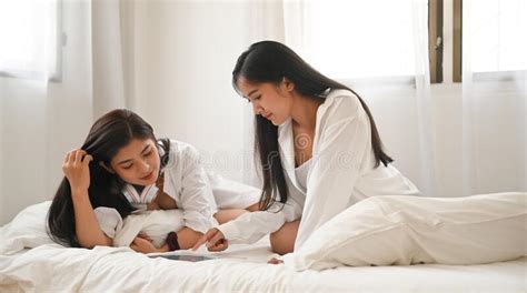 Asian Lesbian Lgbt Couple In White Pajamas Are Using Tablet While
