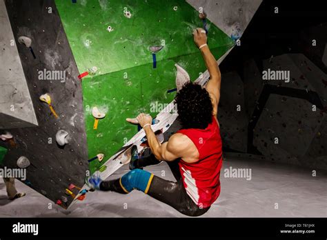 Rock Climber Man Hanging On A Bouldering Climbing Wall Inside On