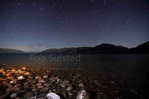 Lake Wanaka At Night With Star Trails Above Moonshine Sheen On Lake