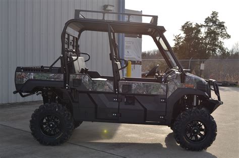 a camo utility vehicle parked in front of a building with the door open
