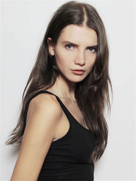 A Woman With Long Brown Hair Wearing A Black Tank Top And Posing For
