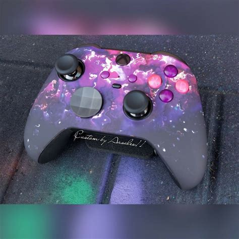 A Close Up Of A Game Controller On A Surface With Blurry Lights In The