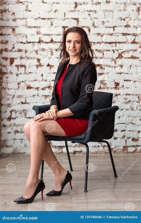 A Young Attractive Business Woman Brunette In A Short Red Dress And