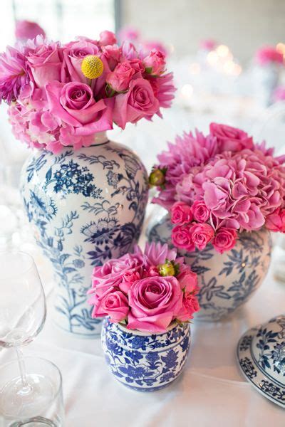 Pink Flowers In Blue And White Vases Sitting On A Table With Plates