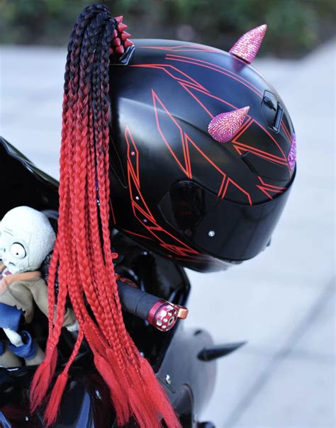 A Black Motorcycle With Red And Pink Braids On It