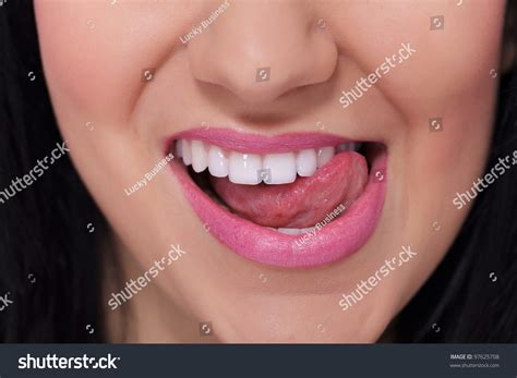 Close Up Of A Female Mouth And White Teeth Which She Touches With Her