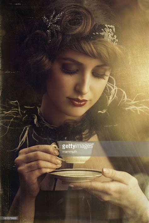 A Woman Holding A Cup And Saucer In Her Hands Looking Down At The Plate