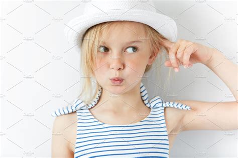 Headshot Of Angry And Irritated Preschool Girl In White Hat And Striped