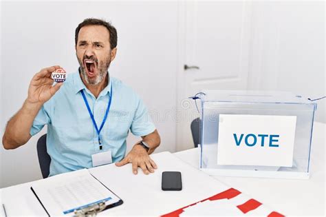 Middle Age Man With Beard Sitting By Ballot Holding I Vote Badge Angry