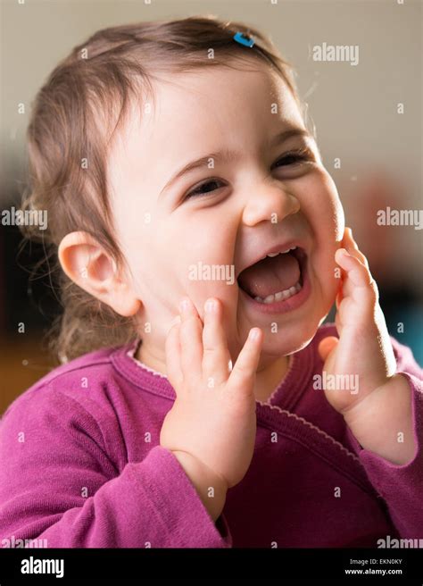 Cute Baby Girl In Purple Looking Aside Laughing Stock Photo Alamy