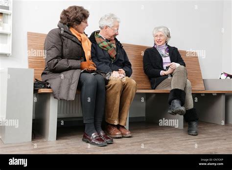 A Couple And An Older Woman Chatting In The Waiting Room Of A Hospital